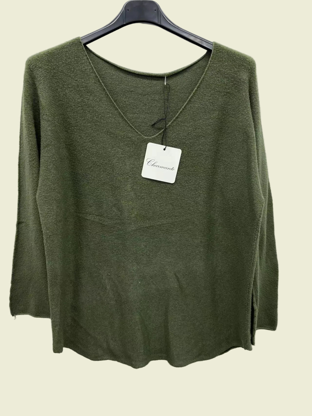 An olive green knit long-sleeve top hanging on a black hanger against a plain white background