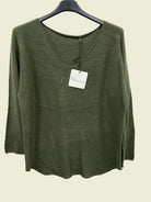 An olive green knit long-sleeve top hanging on a black hanger against a plain white background