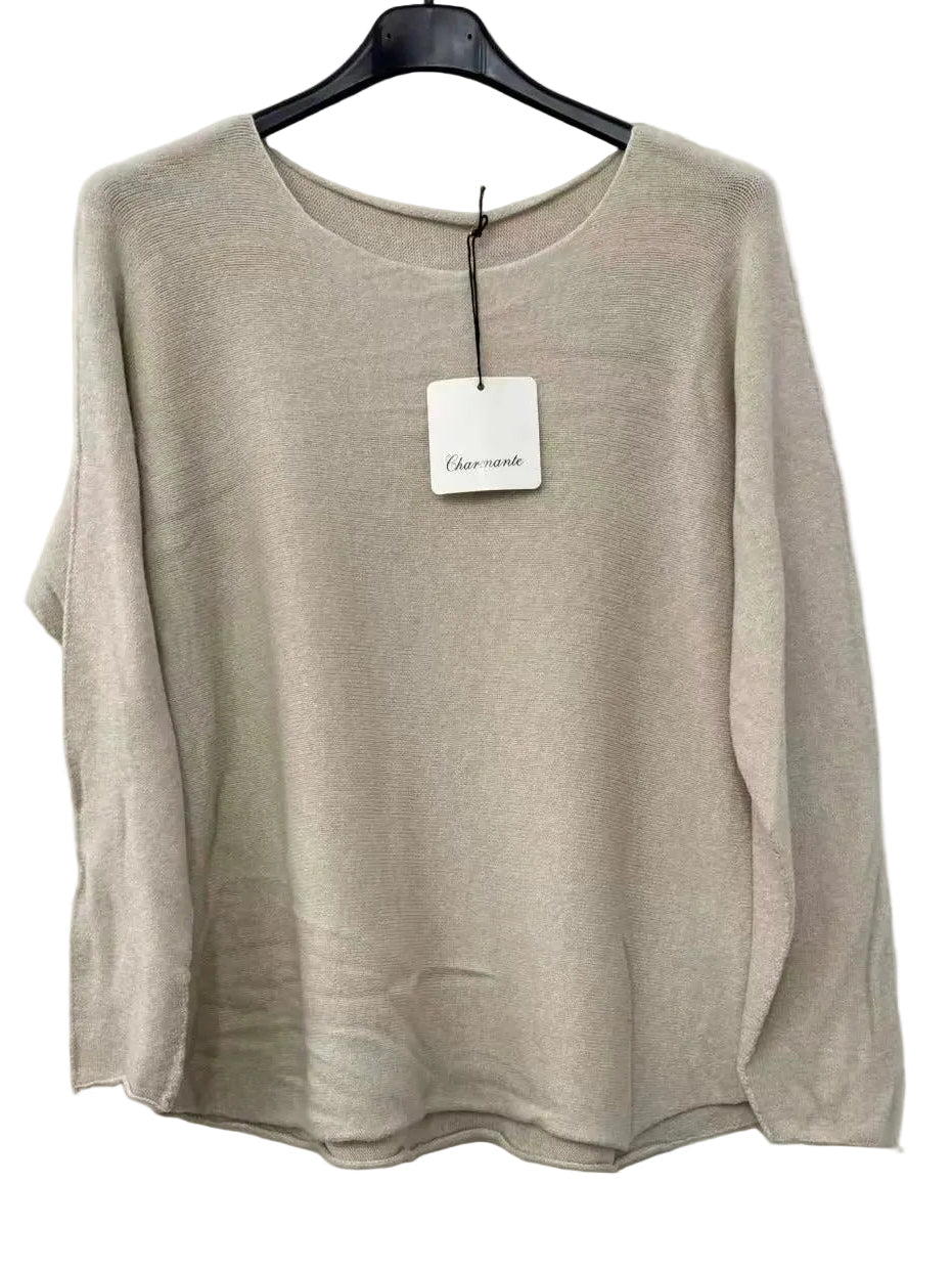A beige knit long-sleeve top hanging on a black hanger against a white wall,