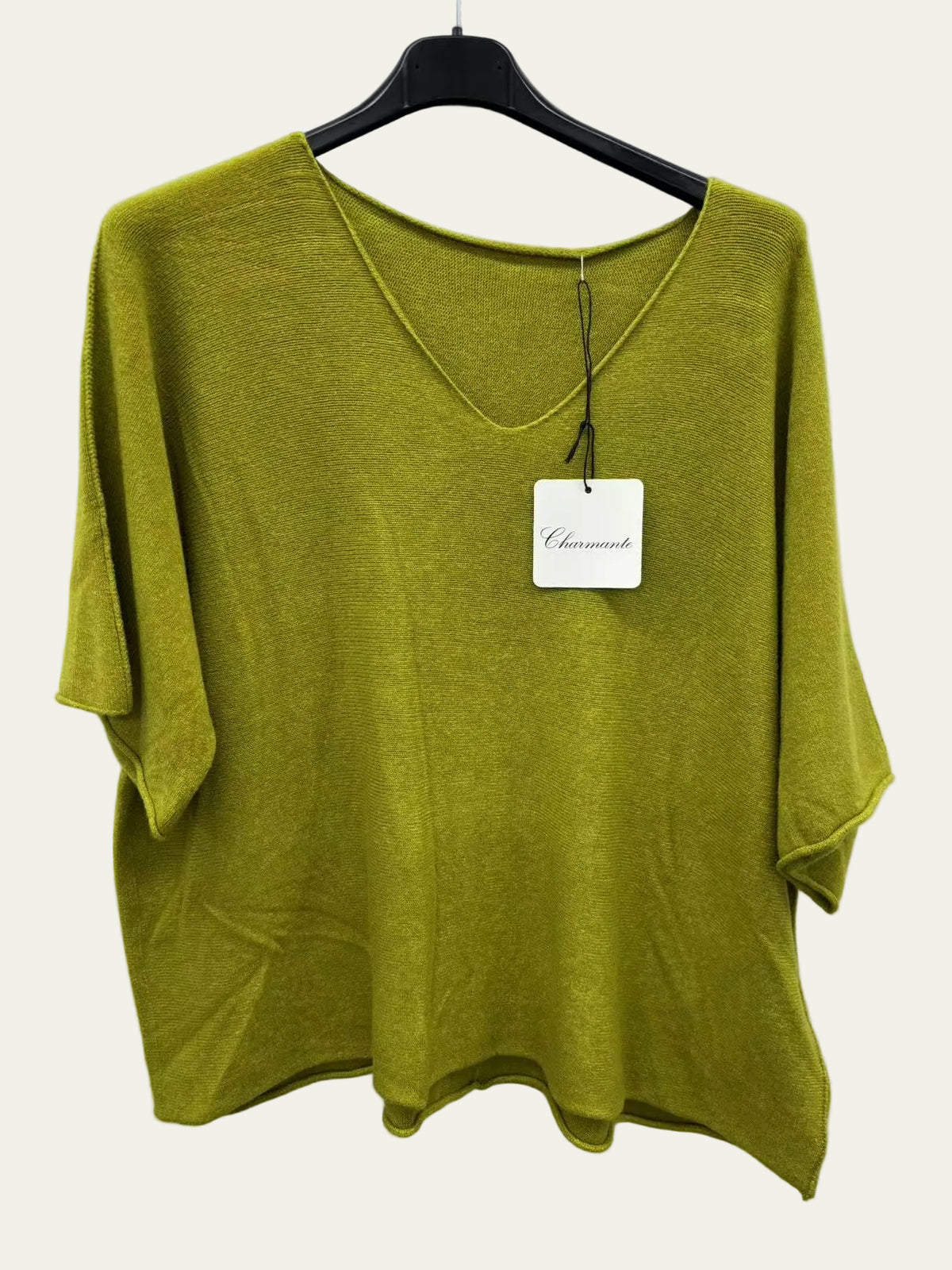 An olive green short-sleeve knit top with a V-neck, hanging on a black hanger against a white wall. 