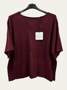 A burgundy short-sleeve V-neck top hanging on a black hanger