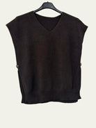 A dark brown sleeveless knit sweater vest with a V-neck and ribbed hem, hanging on a black hanger against a plain white wall.