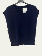 A navy blue sleeveless V-neck knit sweater vest hanging on a black hanger against a white wall. 