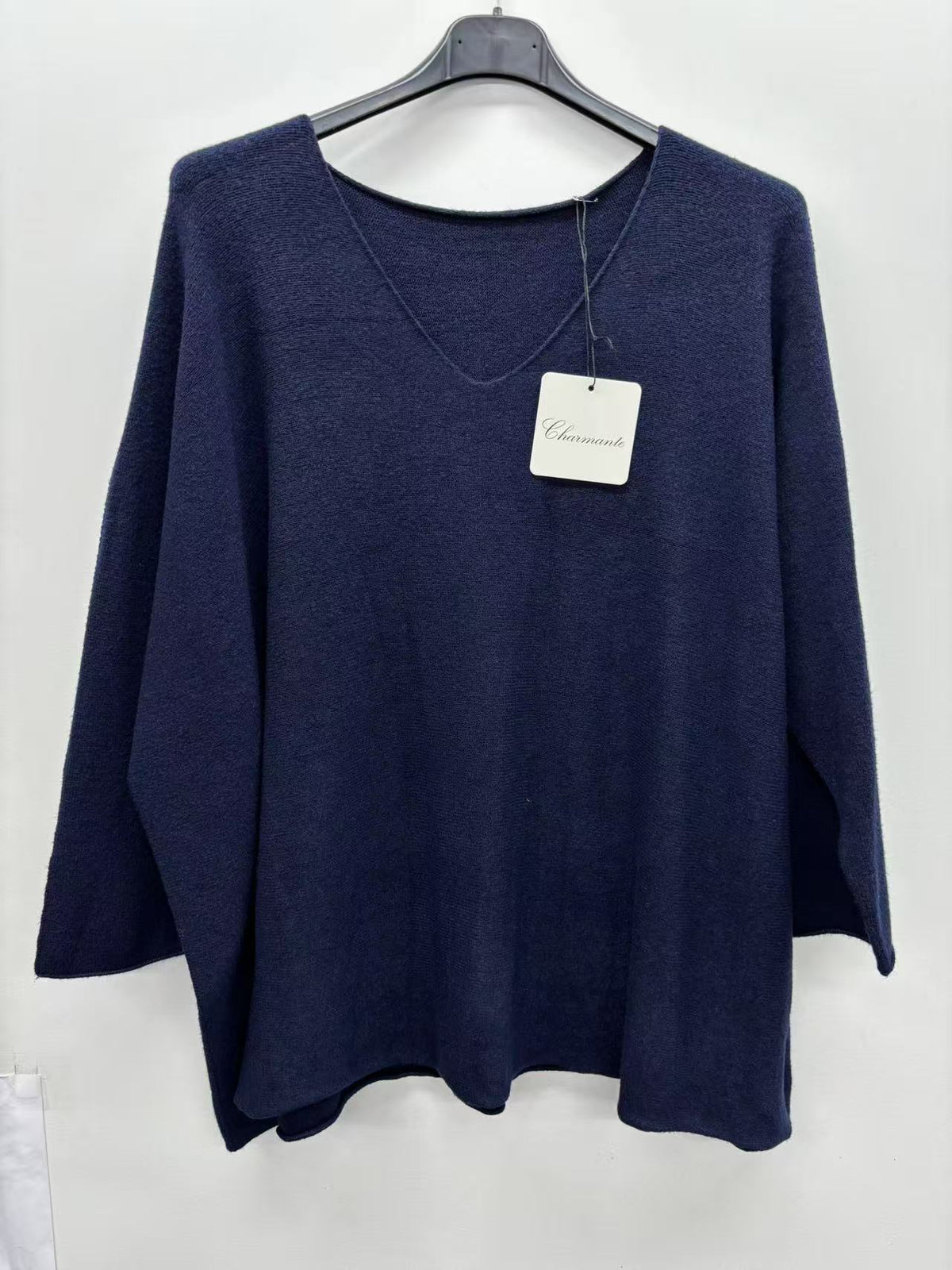 A navy blue knit poncho-style sweater hanging on a black hanger
