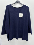 A navy blue knit poncho-style sweater hanging on a black hanger