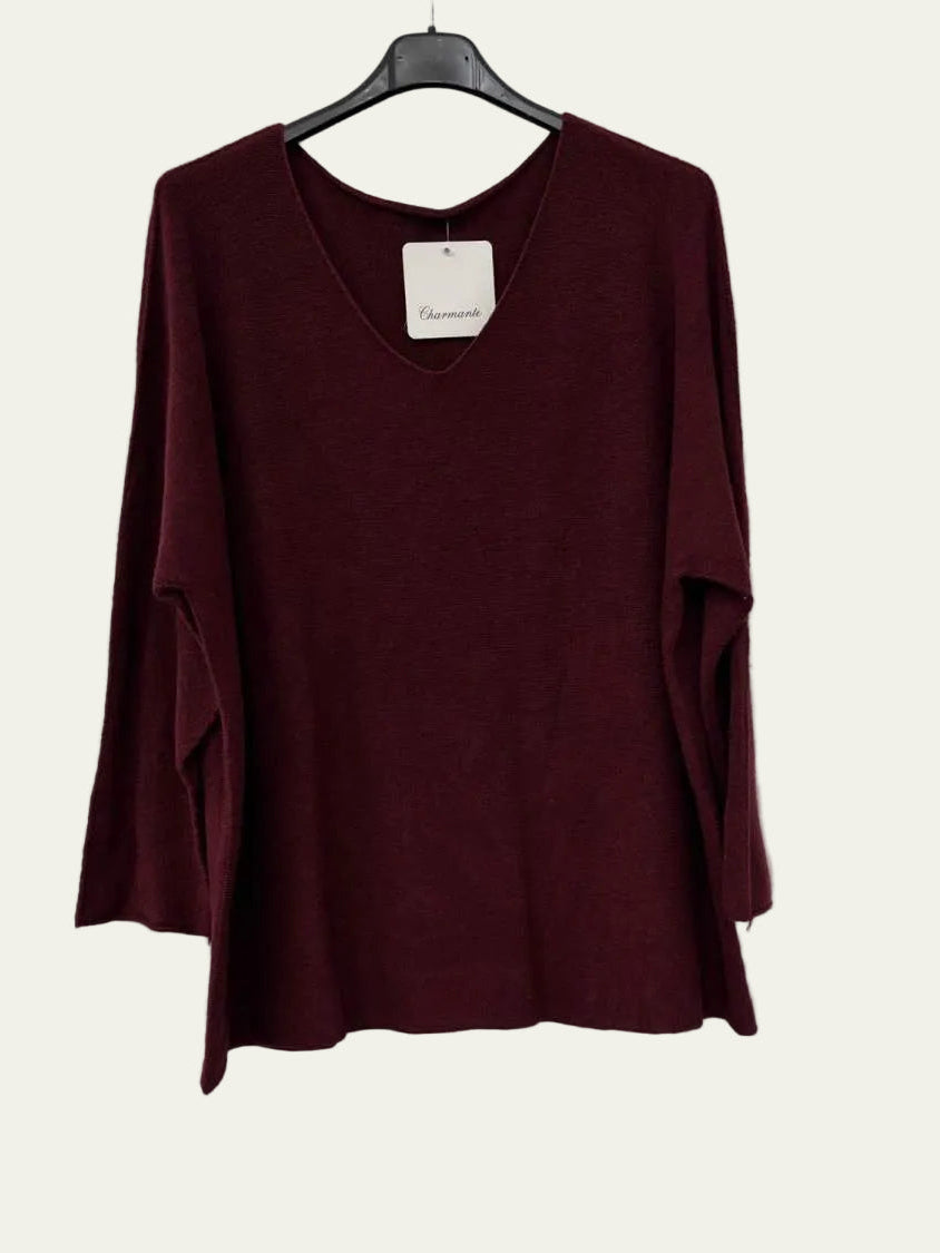 A long-sleeve knit top in deep burgundy hanging on a black hanger