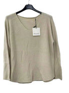 A beige knit long-sleeve top with a V-neck, hanging on a black hanger.