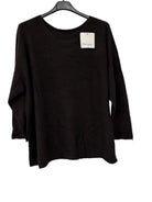 A dark brown long-sleeve knit top hanging on a black hanger against a white wall, with a small white brand tag attached near the neckline.