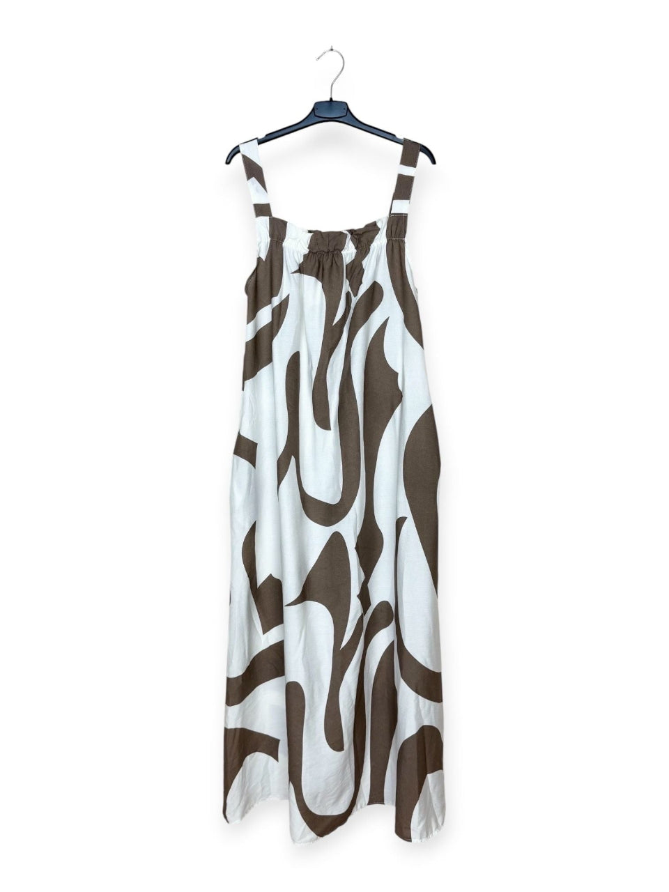 Taupe and white patterned dress on a hanger against a white background