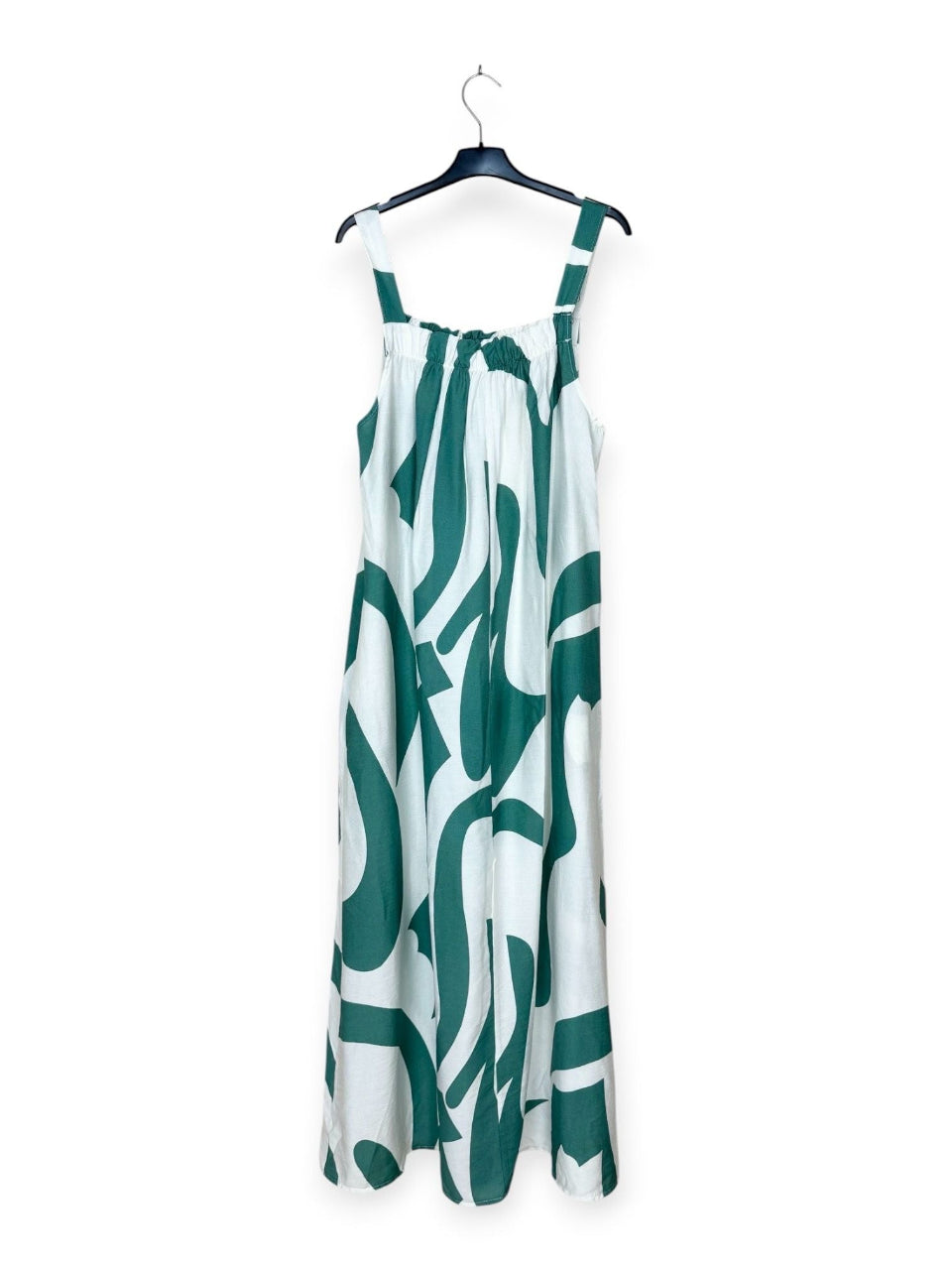 Turquoise and white patterned dress on a hanger against a white background