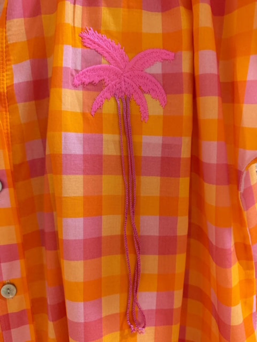 Orange and pink checkered shirt with a pink palm tree design on a blurred background