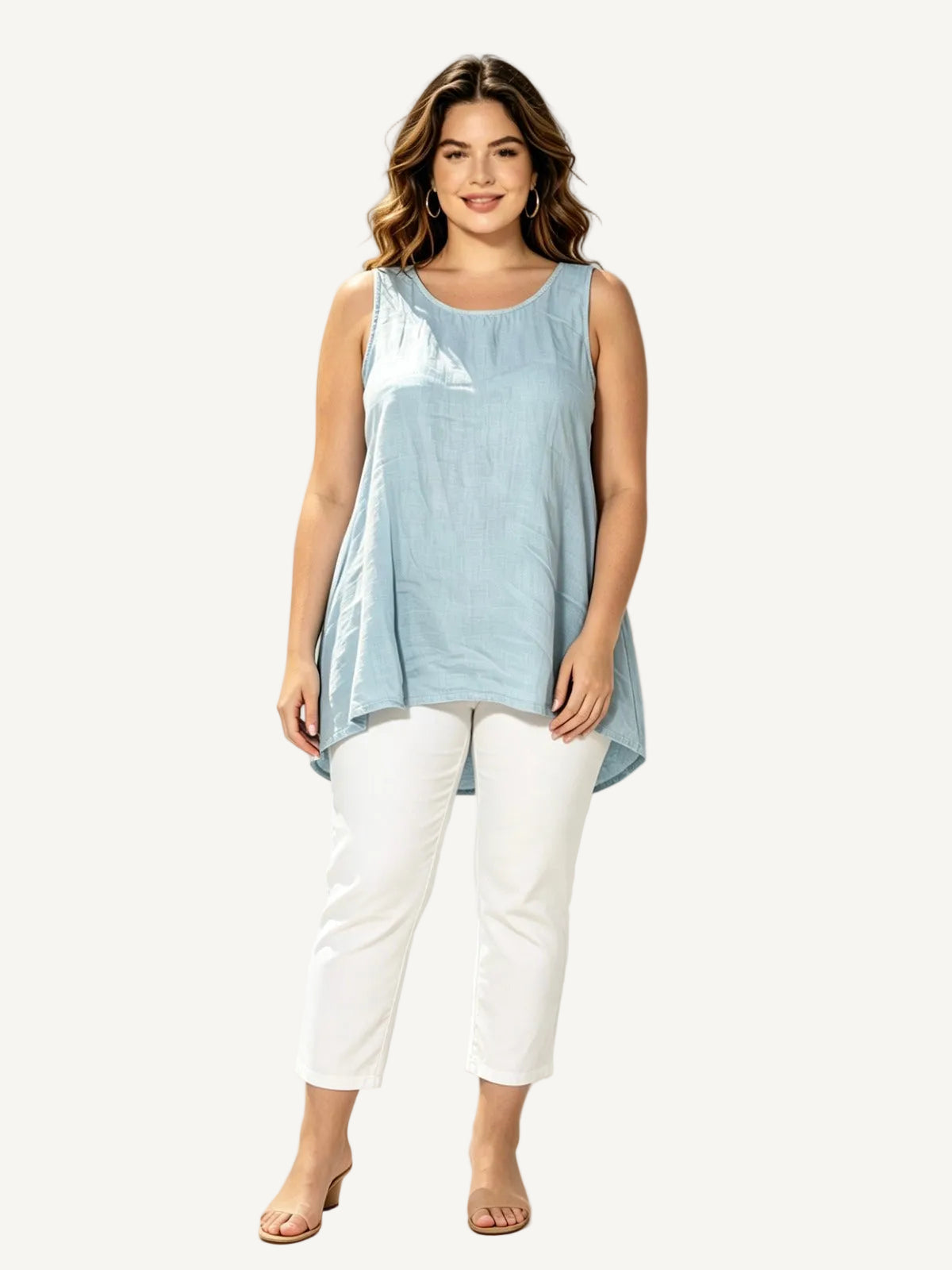 Woman wearing a light blue sleeveless top and white pants against a white background with palm leaves.
