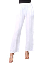 A woman standing against a white background wearing straight leg white trousers with an elasticated waist, paired with a black top. White background
