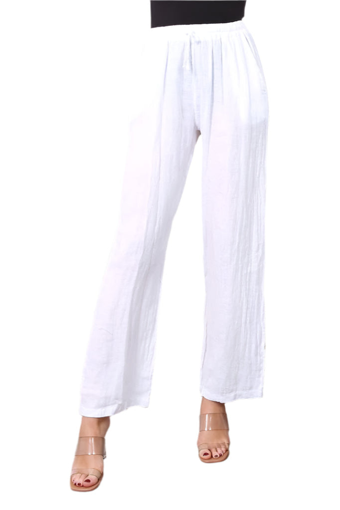 A woman standing against a white background wearing straight leg white trousers with an elasticated waist, paired with a black top. White background