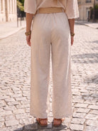 Person wearing beige wide-leg pants on a cobblestone street