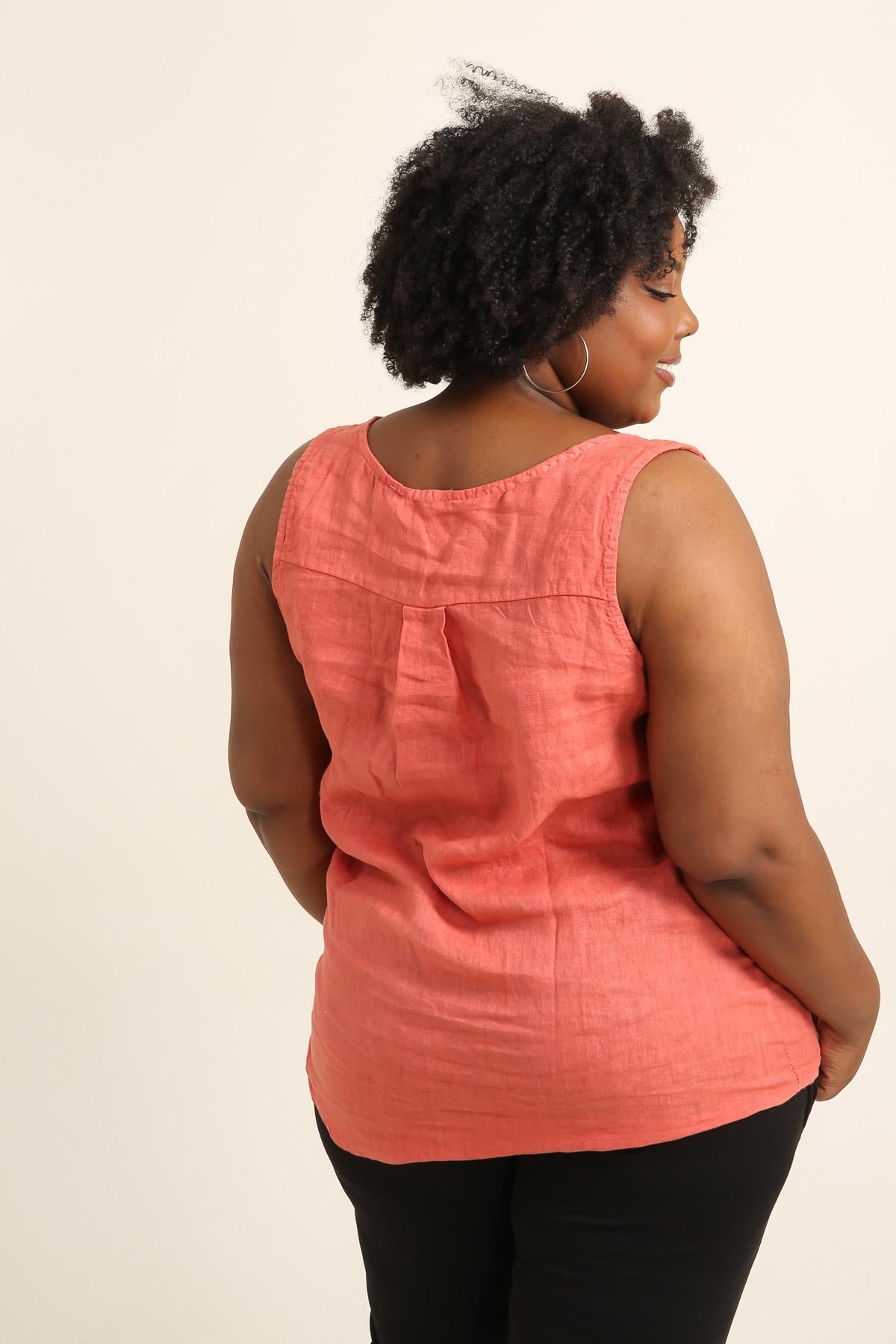 Woman wearing a coral sleeveless top against a beige background