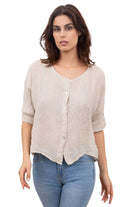 A woman wearing a beige one size pure linen button fronted collarless shirt with three quarter sleeves, paired with blue jeans.