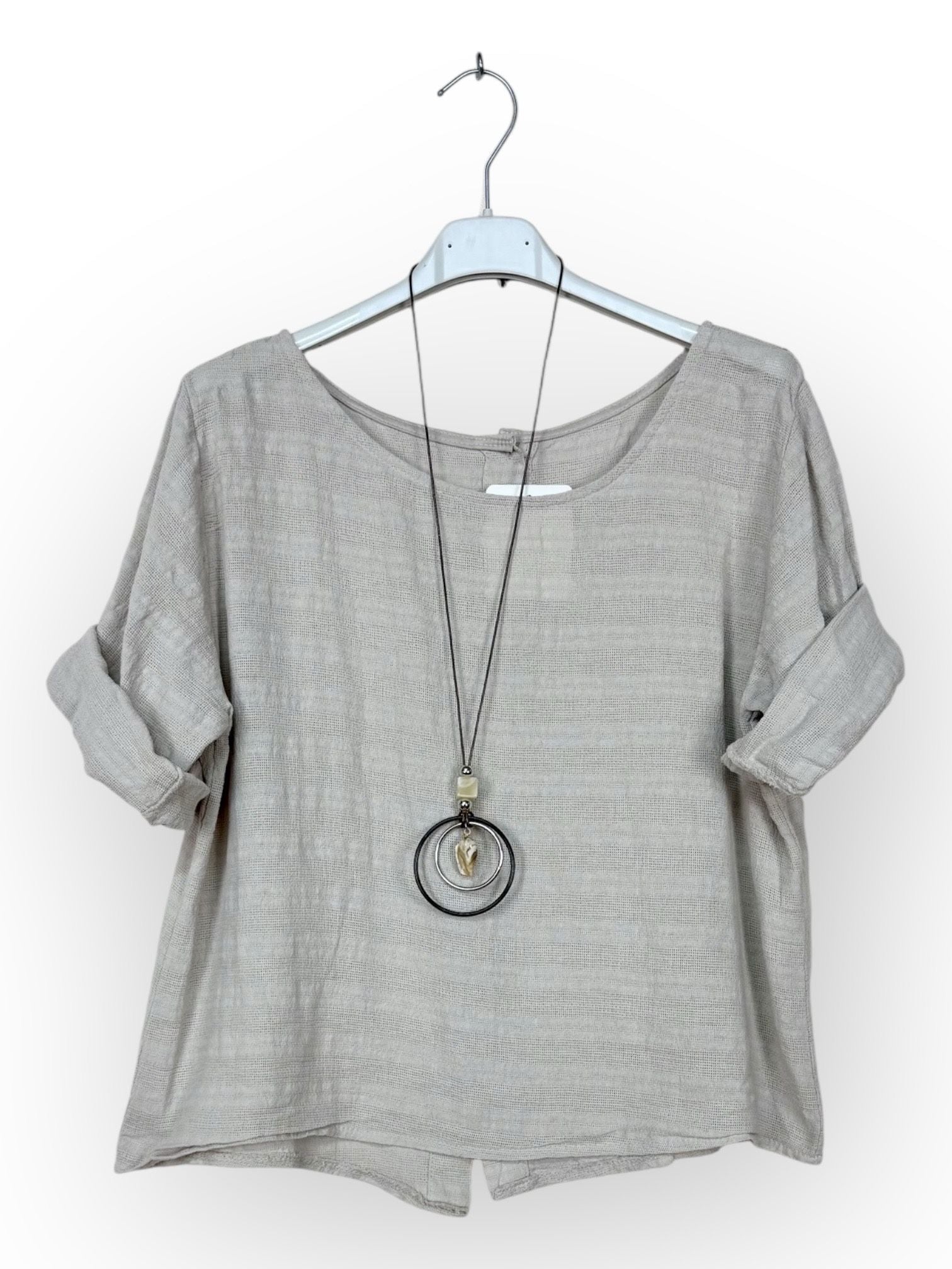 beige cotton top with a long necklace on a hanger against a white background