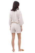 Woman wearing a beige outfit with a jacket and shorts on a white background