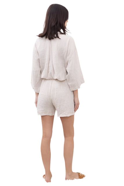 Woman wearing a beige outfit with a jacket and shorts on a white background