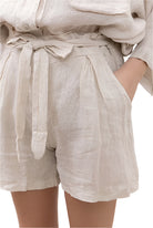 Beige linen shorts with a tie waist on a white background