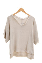 Beige top on a wooden hanger against a white background