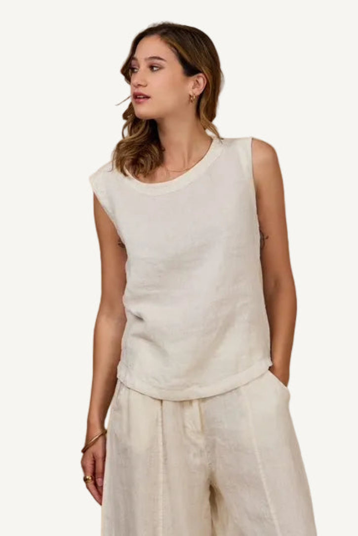 Woman wearing a beige sleeveless top and pants against a beige background
