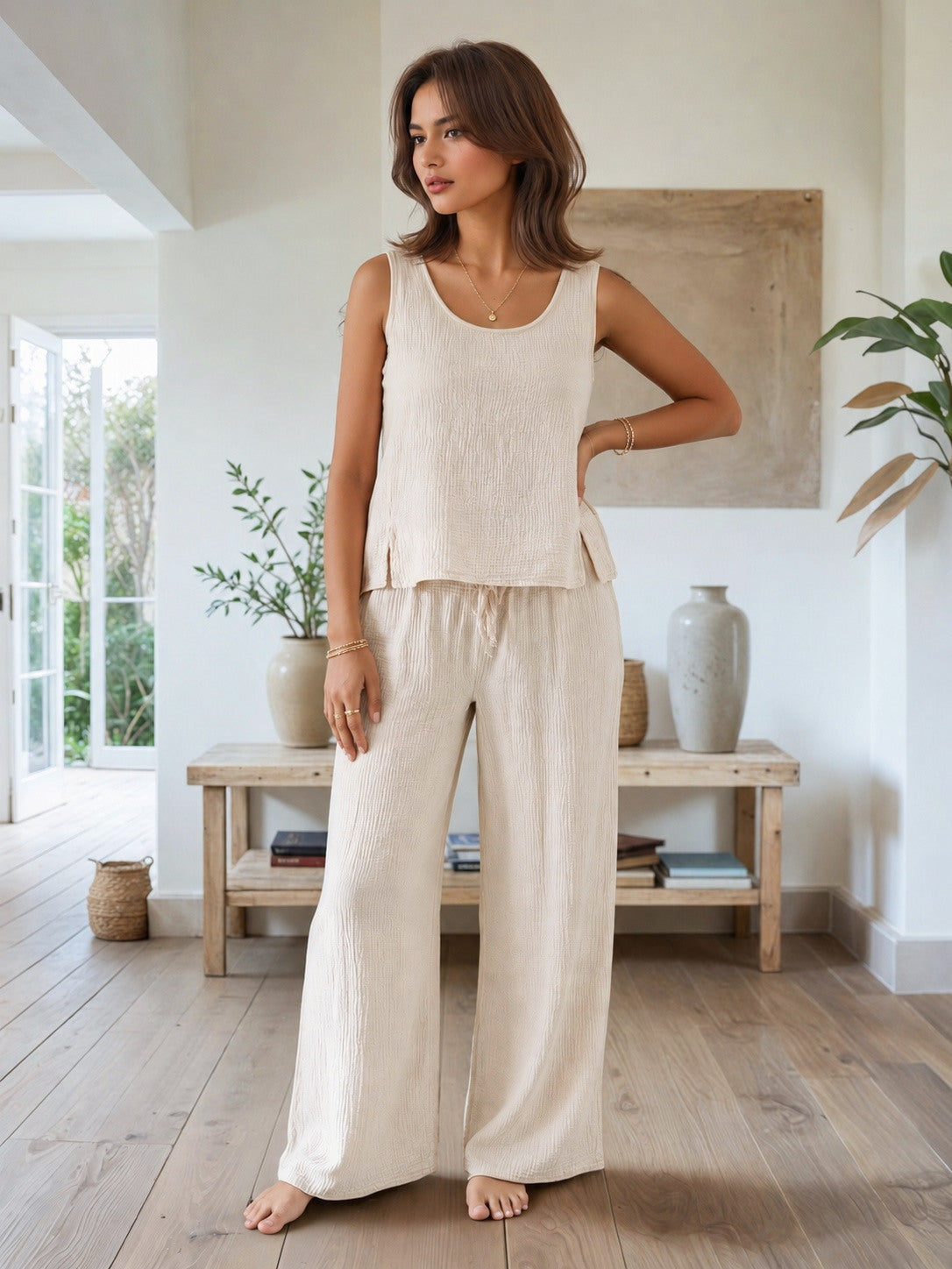 Woman wearing a beige sleeveless top and pants in a bright, minimalistic room.