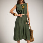 A woman models a sleeveless olive green midi dress with a thin tan belt