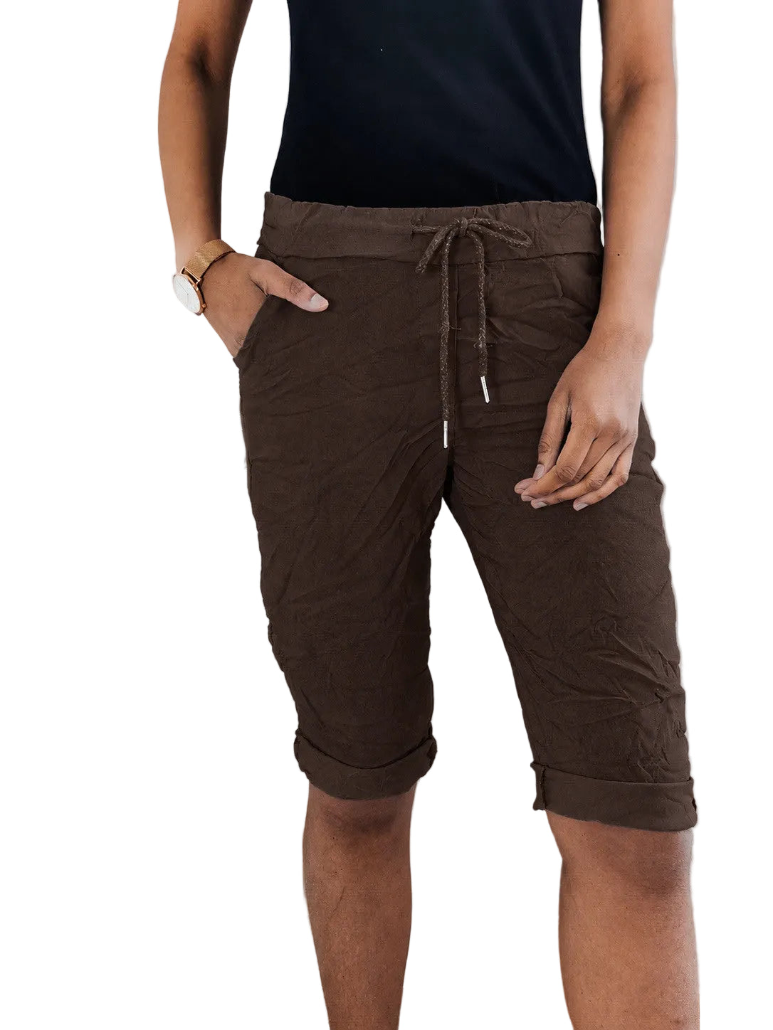 A person wearing dark brown drawstring capri pants with side pockets, paired with a black sleeveless top, standing in front of a white radiator.