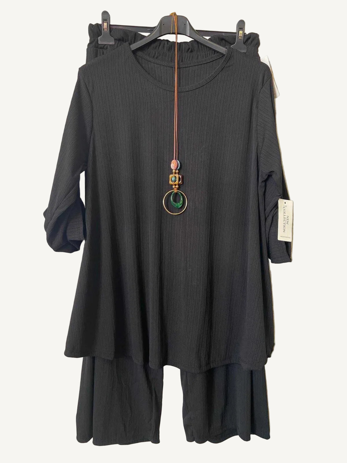 Black trouser and top set plus size a hanger with a textured gray background