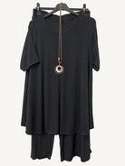 Black outfit with a necklace on a hanger against a textured white background