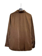 A brown long-sleeve collared shirt or blouse hanging on a black hanger against a plain white backdrop.