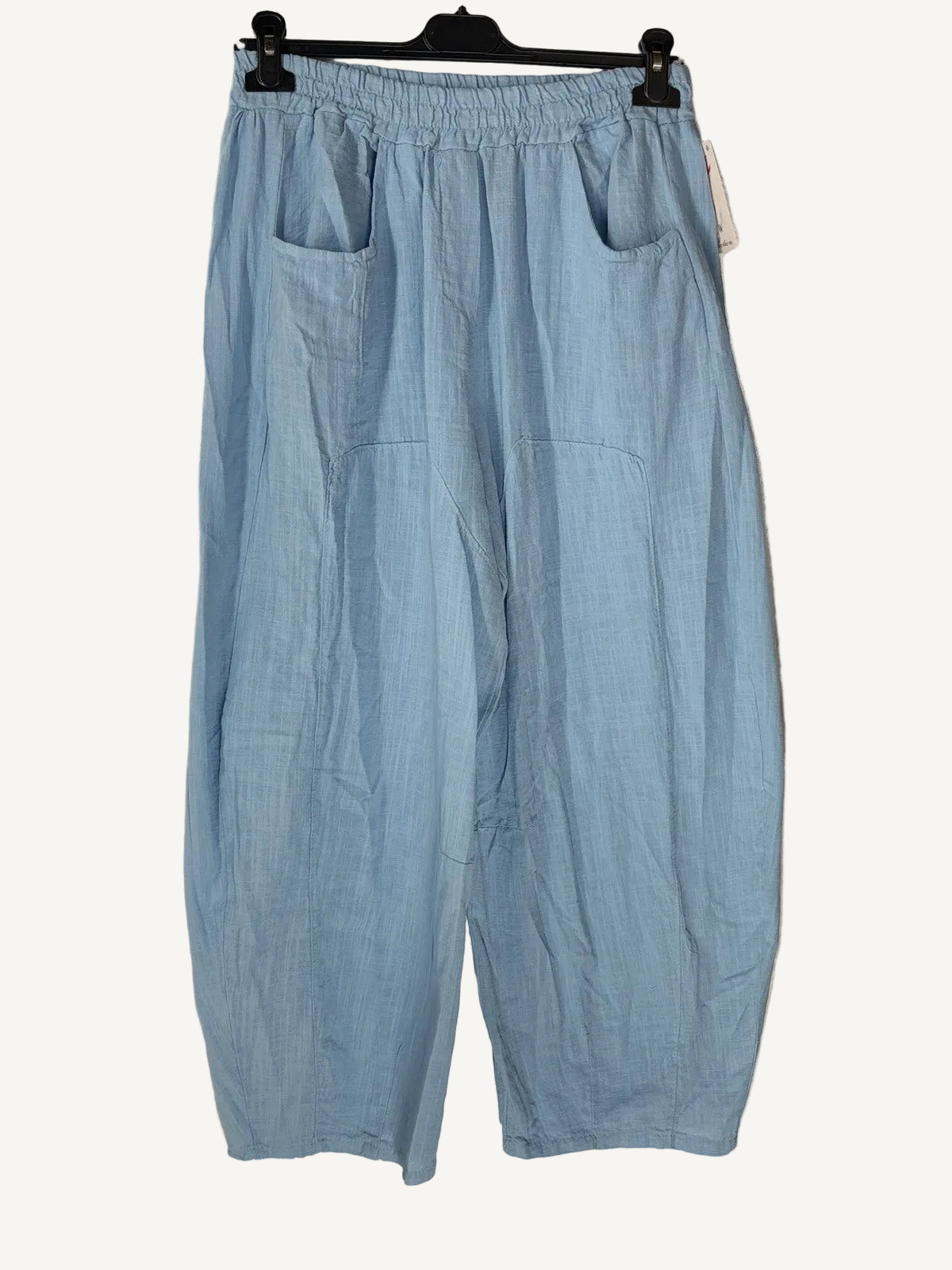 Light blue pants hanging on a hanger against a neutral background