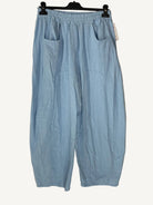 Light blue pants hanging on a hanger against a neutral background