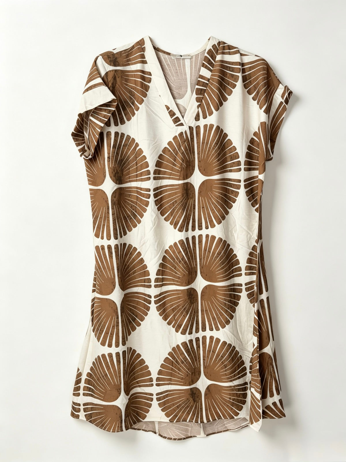 A short-sleeve V-neck dress featuring a bold brown and cream geometric floral pattern, displayed flat against a light off-white background.