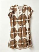 A short-sleeve V-neck dress featuring a bold brown and cream geometric floral pattern, displayed flat against a light off-white background.