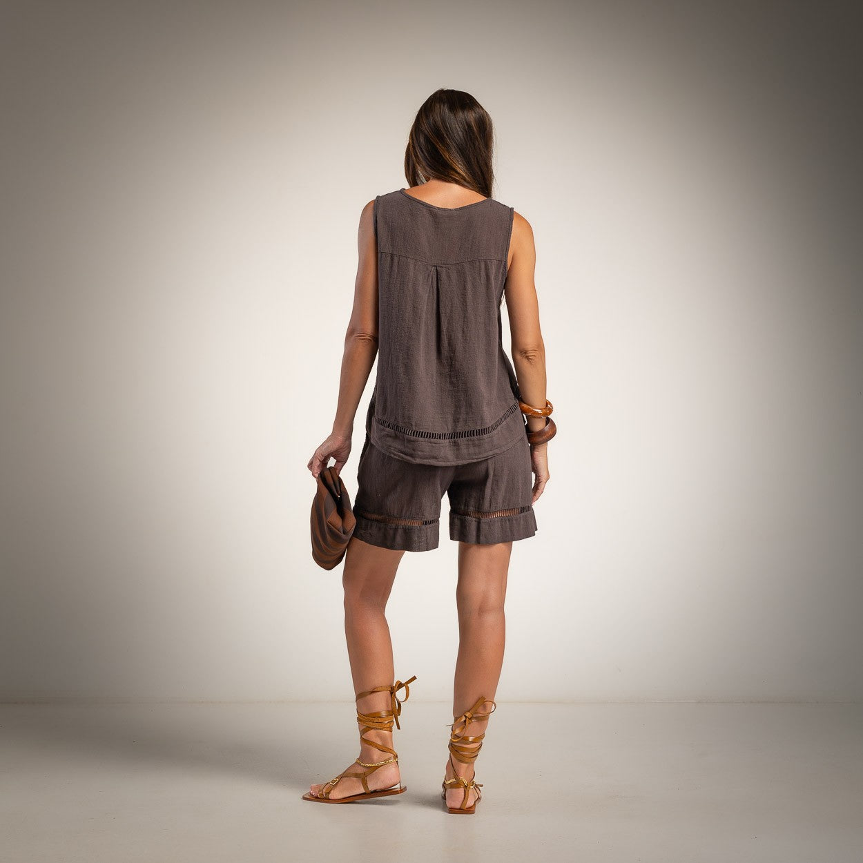 A woman is shown from behind wearing a sleeveless brown linen top and matching shorts