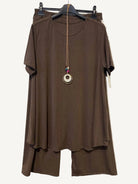 Brown two piece trouser set with a necklace on a hanger against a textured white background
