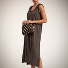 A woman wearing a sleeveless brown midi dress with side slits