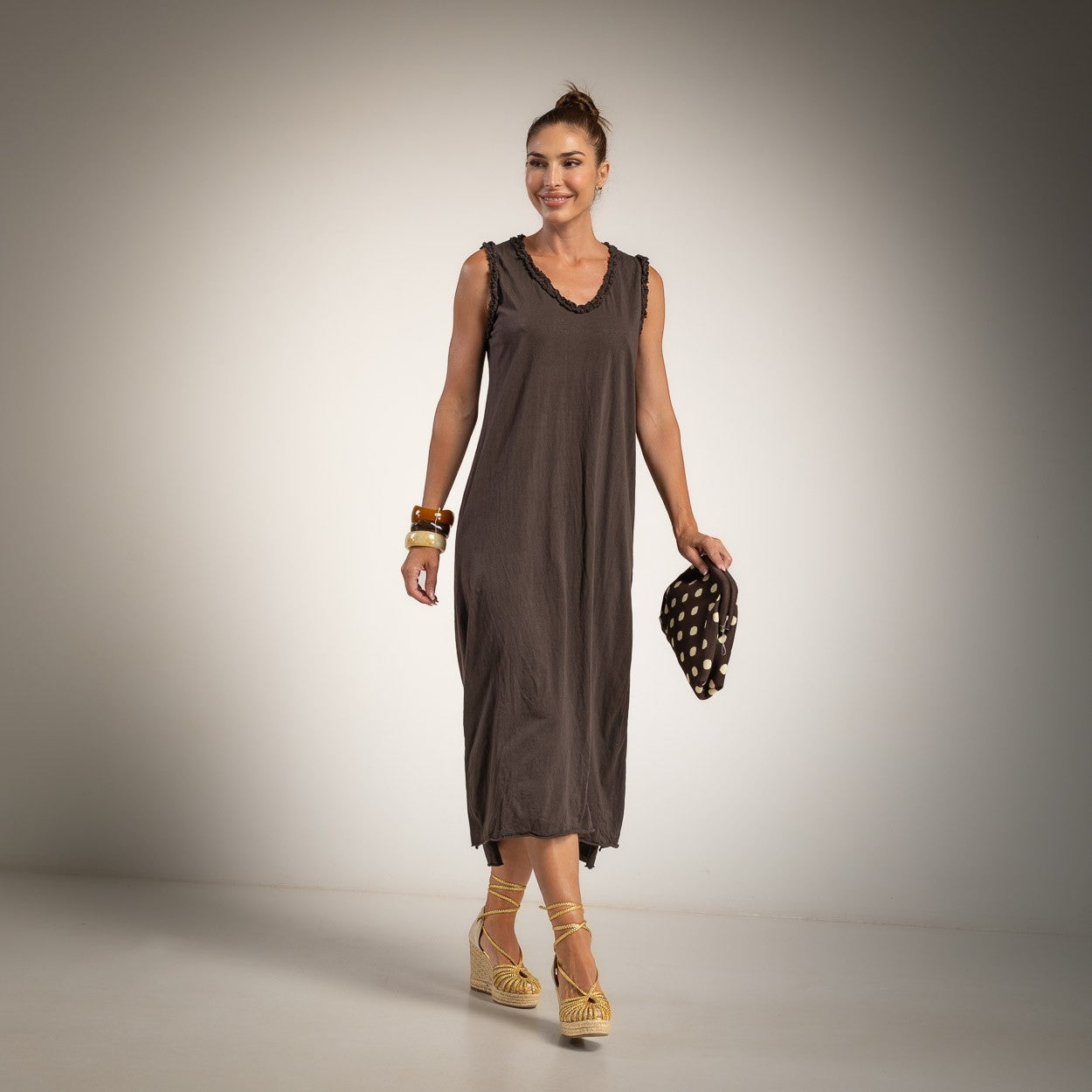 A woman modeling a sleeveless, dark brown midi dress with v neck