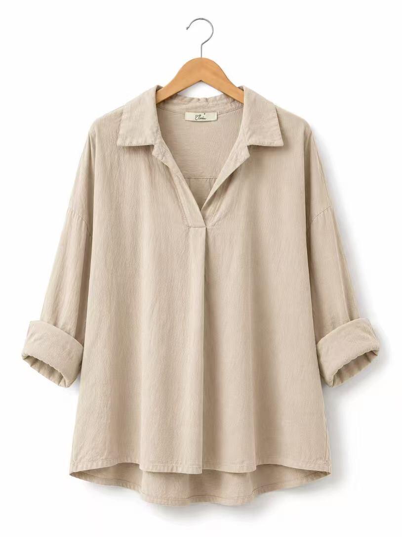 A beige long-sleeve linen shirt with a collar and rolled cuffs, hanging on a wooden hanger against a white background.