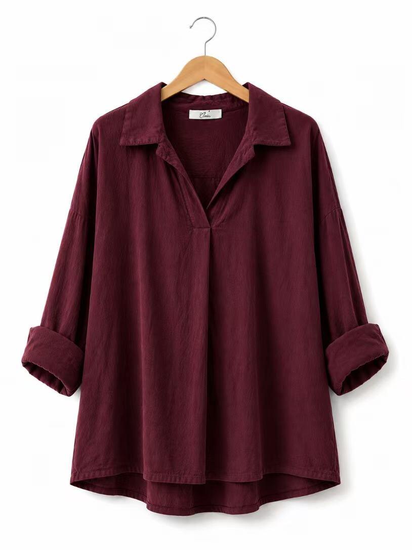 A dark burgundy long-sleeve shirt with a relaxed fit, a collar, and rolled cuffs, hanging on a wooden hanger against a plain white background.