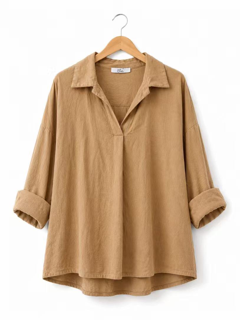 A tan long-sleeve linen shirt with a collar and rolled cuffs, hanging on a wooden hanger against a white background.