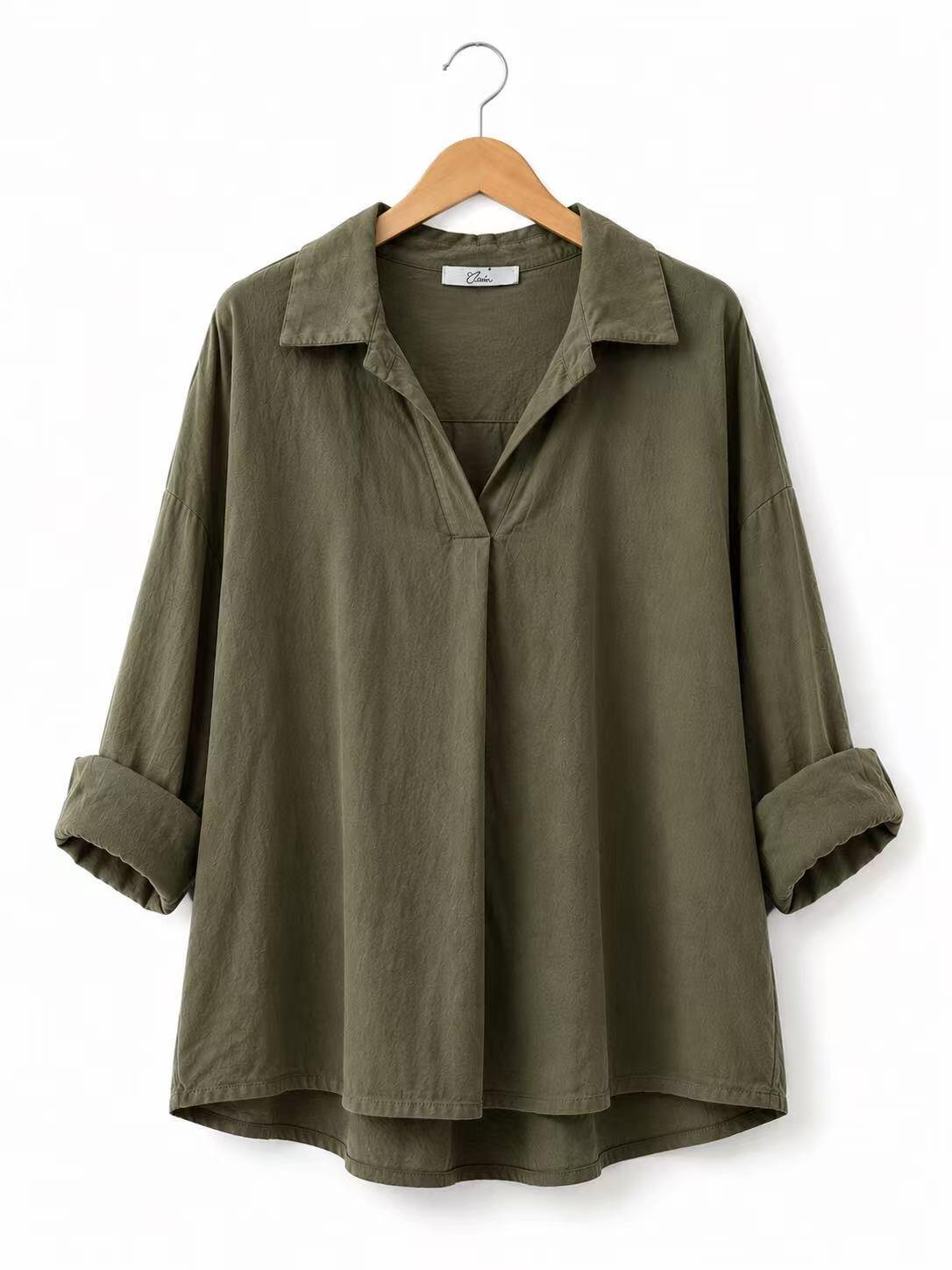 An olive green long-sleeve collared shirt with rolled cuffs, hanging on a wooden hanger against a plain white background.