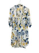 A long-sleeve, open-front tunic with a swirling abstract floral pattern in navy blue, mustard yellow, and gray on a white background, hanging on a white hanger against a white wall.