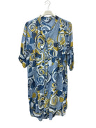 A lightweight button-front shirt dress with a blue, yellow, and white abstract swirl pattern, hanging on a white hanger against a plain white wall.