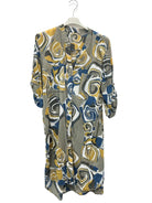 A long-sleeved button-up shirt dress with an abstract swirl pattern in gray, mustard yellow, navy blue, and white, hanging on a white plastic hanger against a plain white wall.