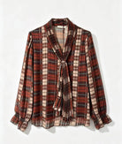 A long-sleeve plaid blouse with a shawl collar, front tie, and ruffled cuffs, shown flat against a white background.