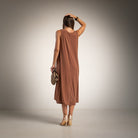 A woman is shown from behind wearing a sleeveless, brown midi dress